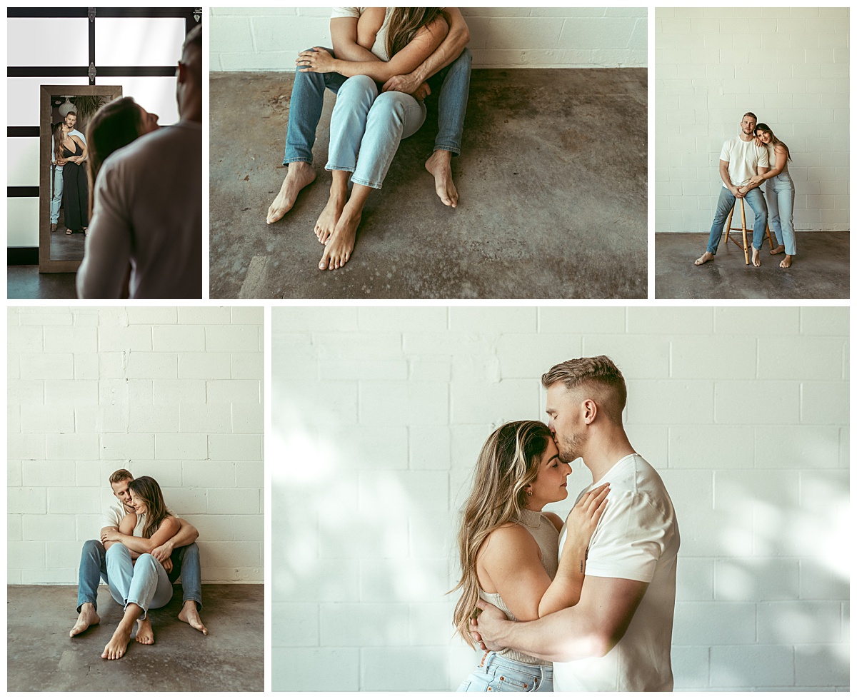 man and woman hold each other in front of white brick wall in studio at couples session