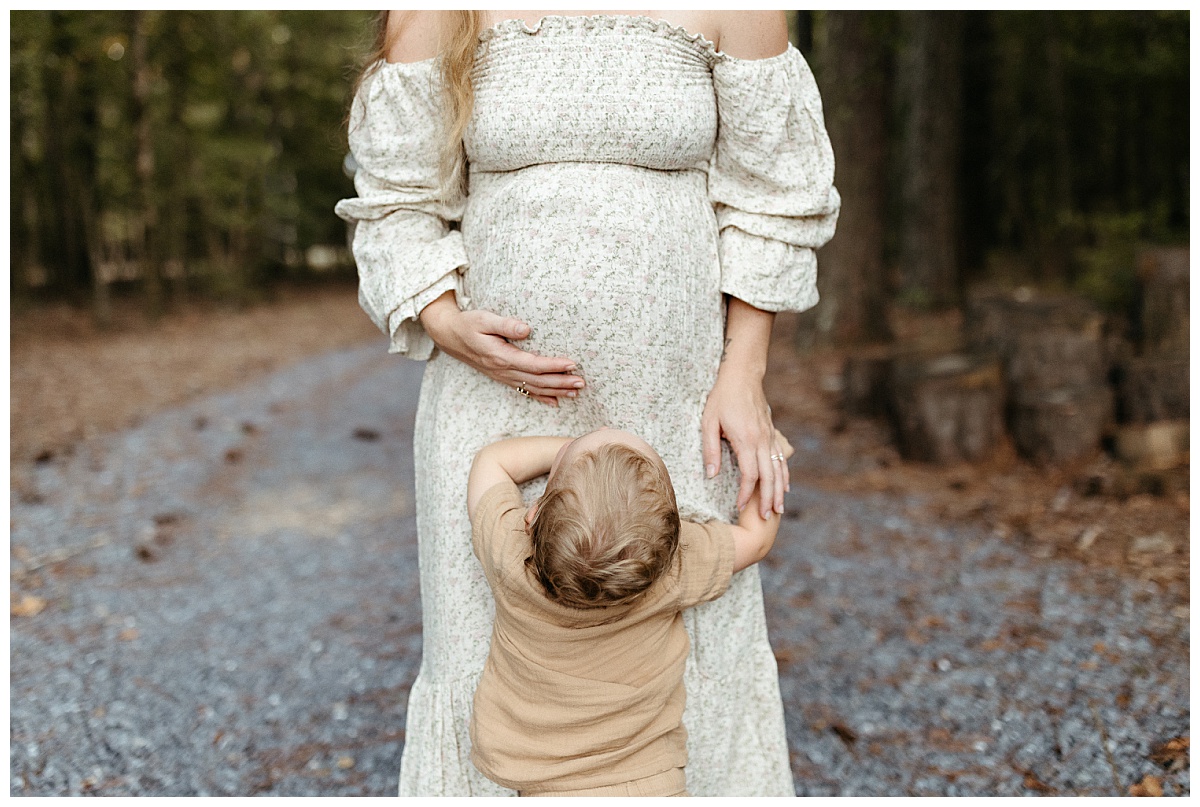 woman holds pregnant belly as small child looks up at her by Virginia Lifestyle Photographer