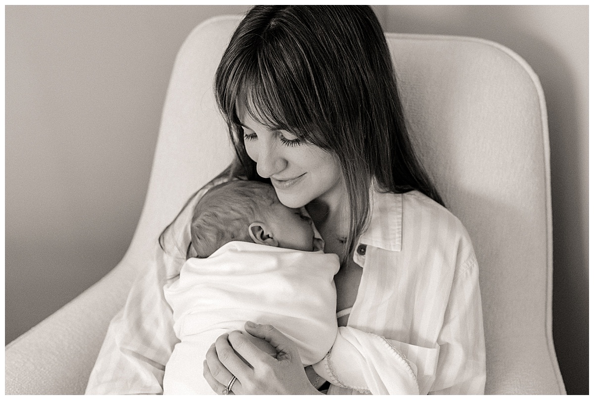 swaddled infant snuggles on mom's chest by Nikki Meer Photography