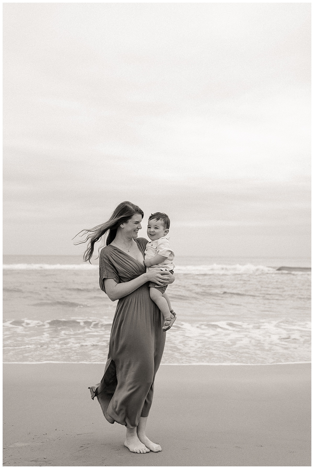 mother smiles as she carries her son by Nikki Meer Photography