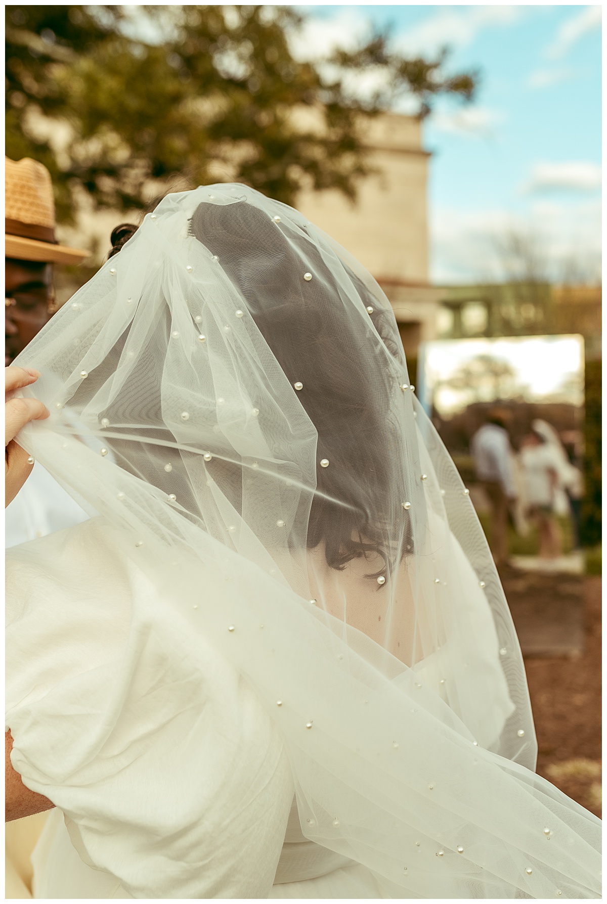 bride holds veil as it blows in wind during wedding portrait session