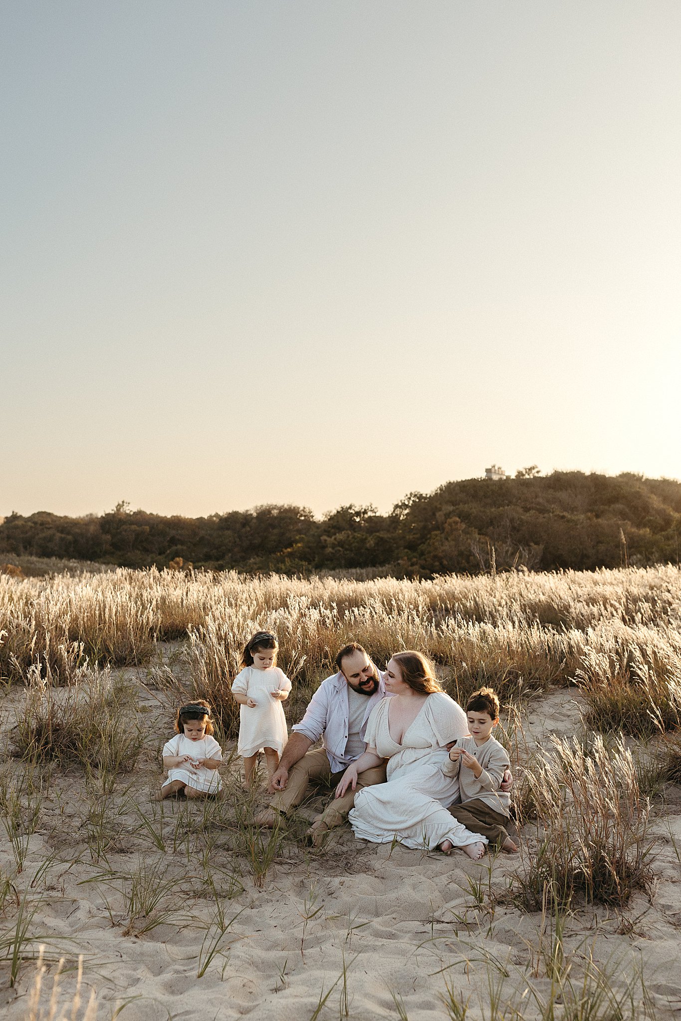 loved ones sit together in sand during perfect family session 