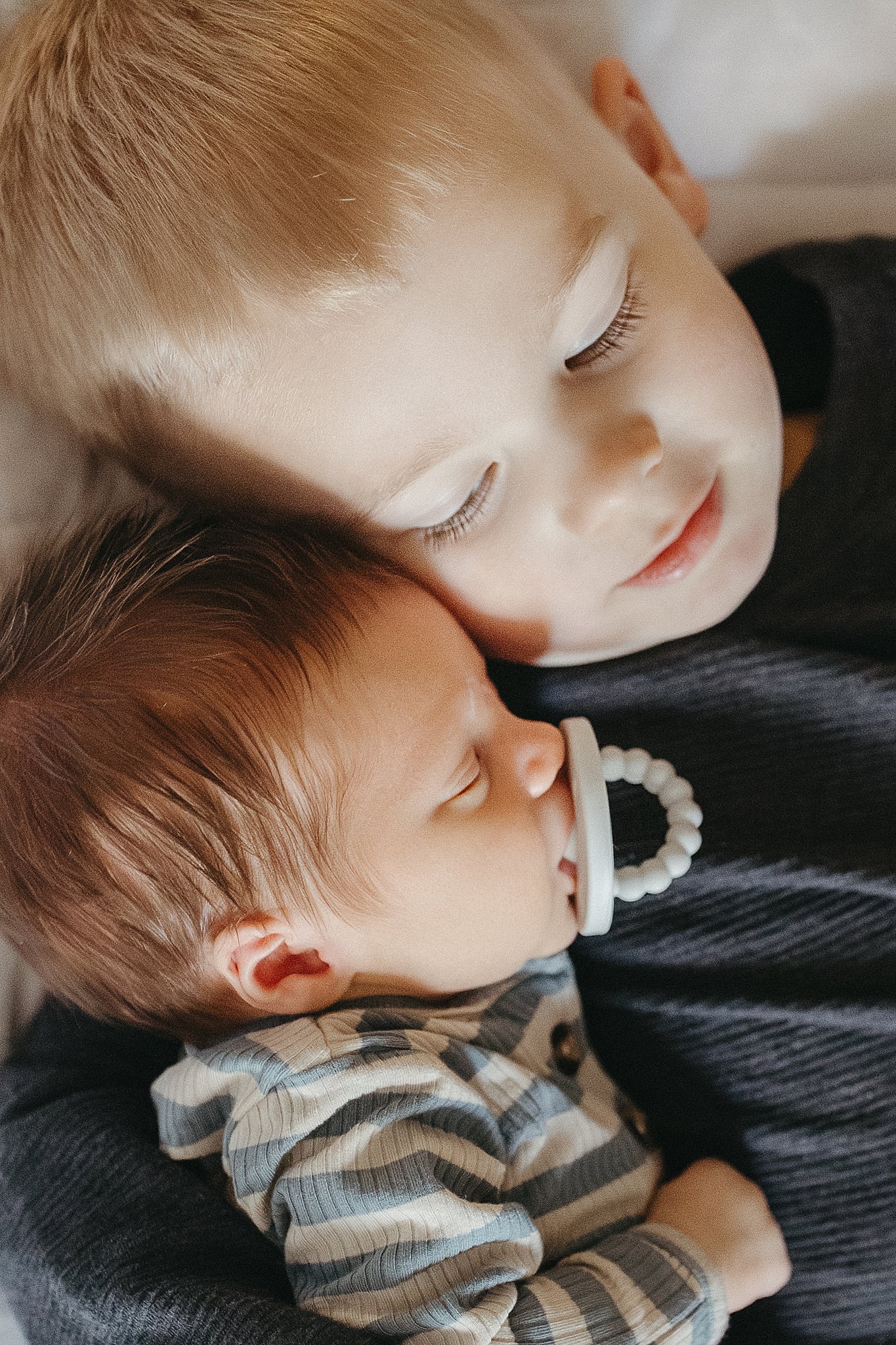 big brother snuggles little brother during in-home newborn session with siblings