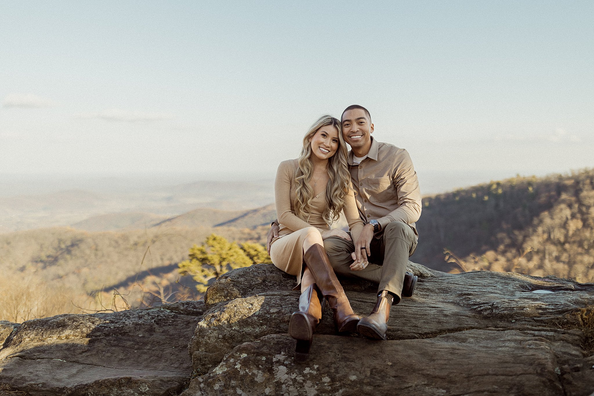 couple sits together on rock overlooking mountains at Shenandoah National Park Couples Session
