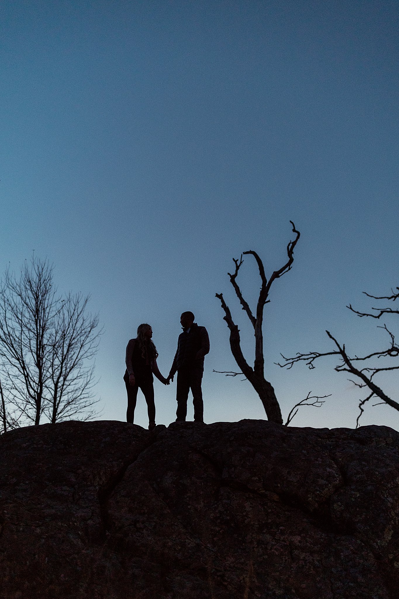 couple stands on hill during blue hour holding hands by Nikki Meer Photography