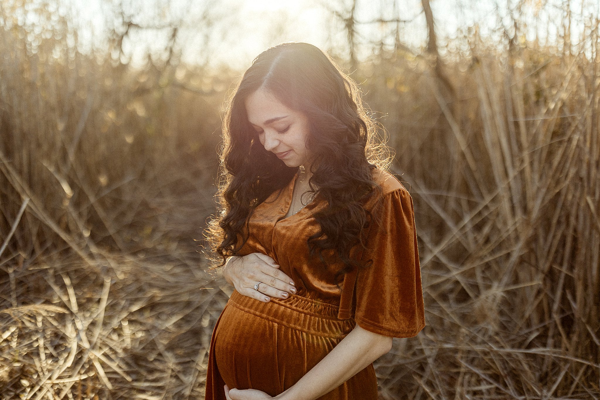 mom to be holds her pregnant belly during Outdoor Maternity Session