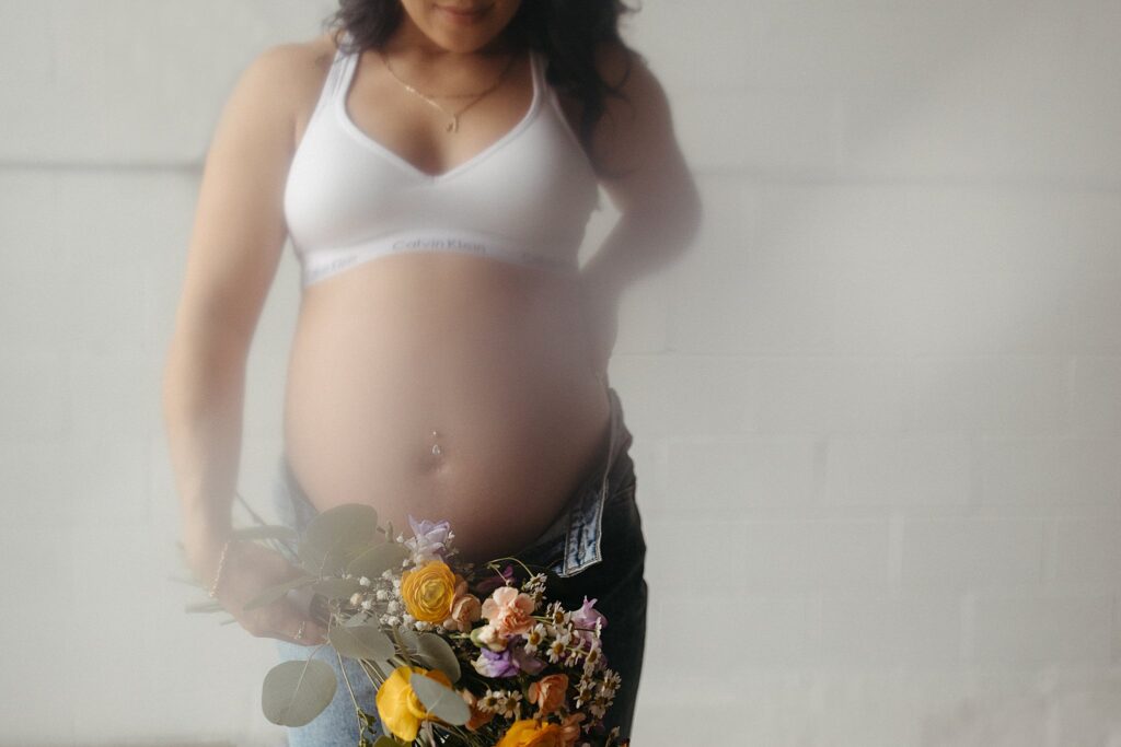 pregnant woman holds flowers for Studio Muse Maternity Session
