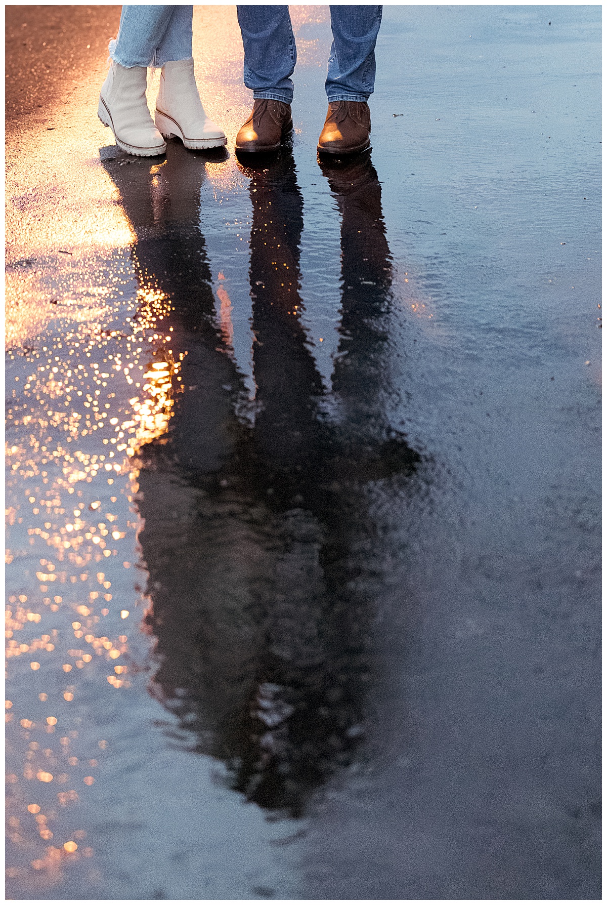two people stand on wet pavement showing just their boots and the bottom of their pants by Nikki Meer Photography