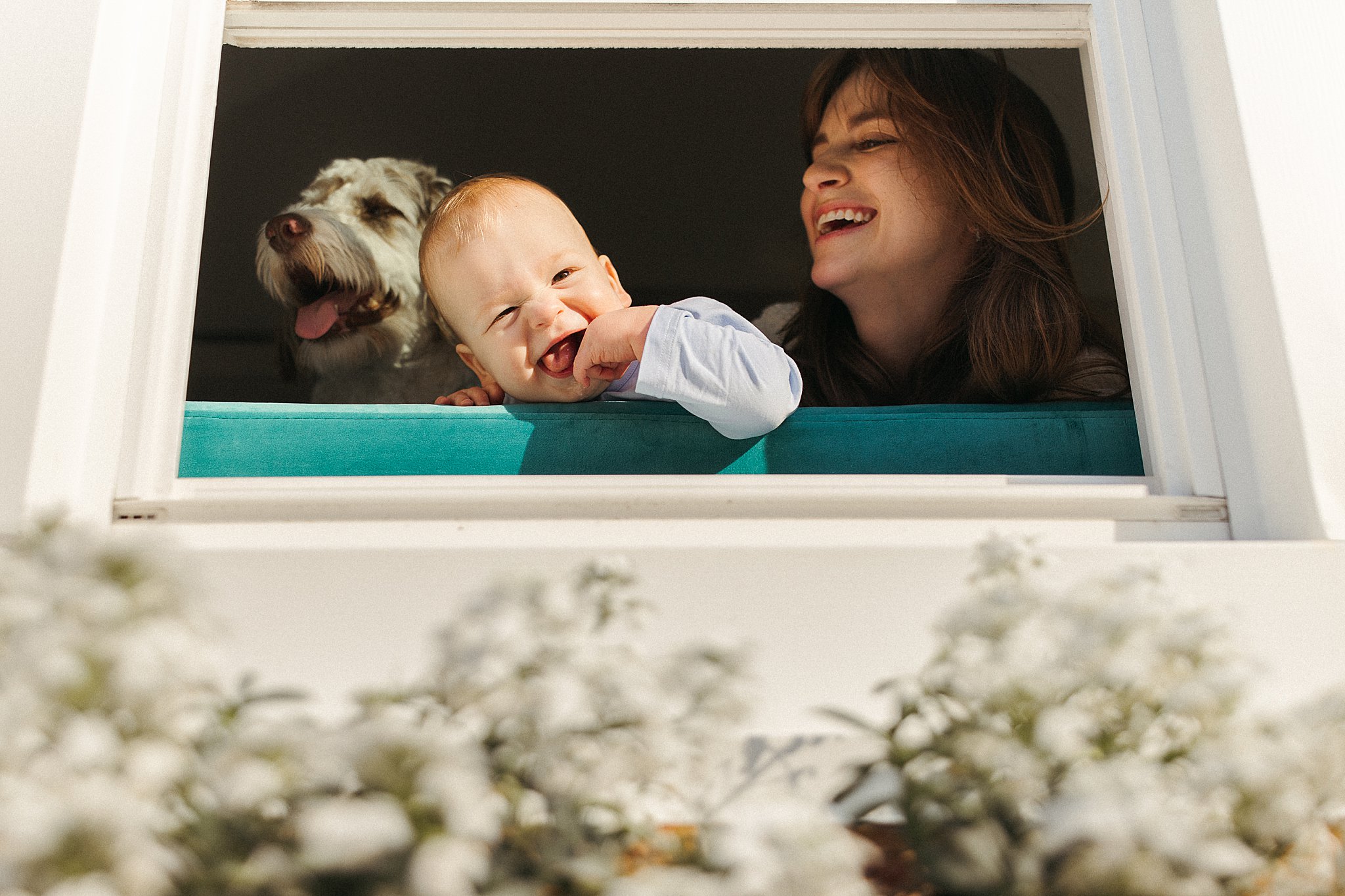 mom smiles as toddler leans on window by Virginia Beach photographer